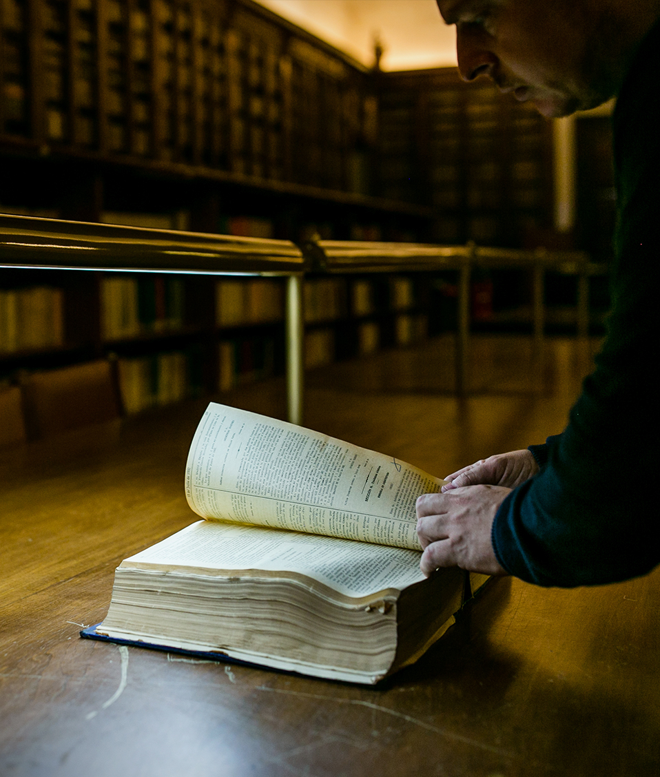 Persona leyendo un libro antiguo en la biblioteca del Hospital Real