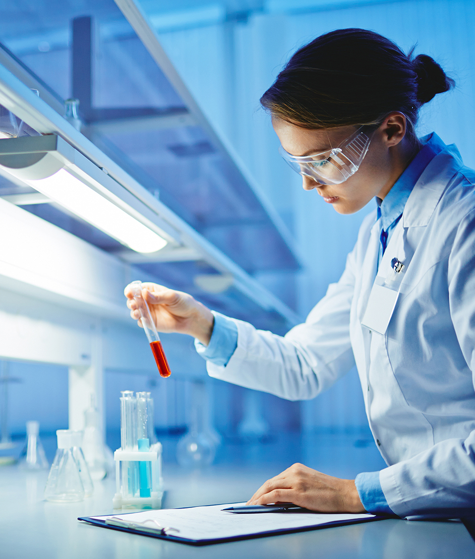 Investigadora manipulando una probeta con un líquido color rojo en un laboratorio