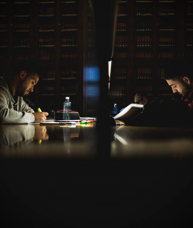 Estudiantes en las mesas de estudio de la biblioteca del Hospital Real leyendo sus apuntes