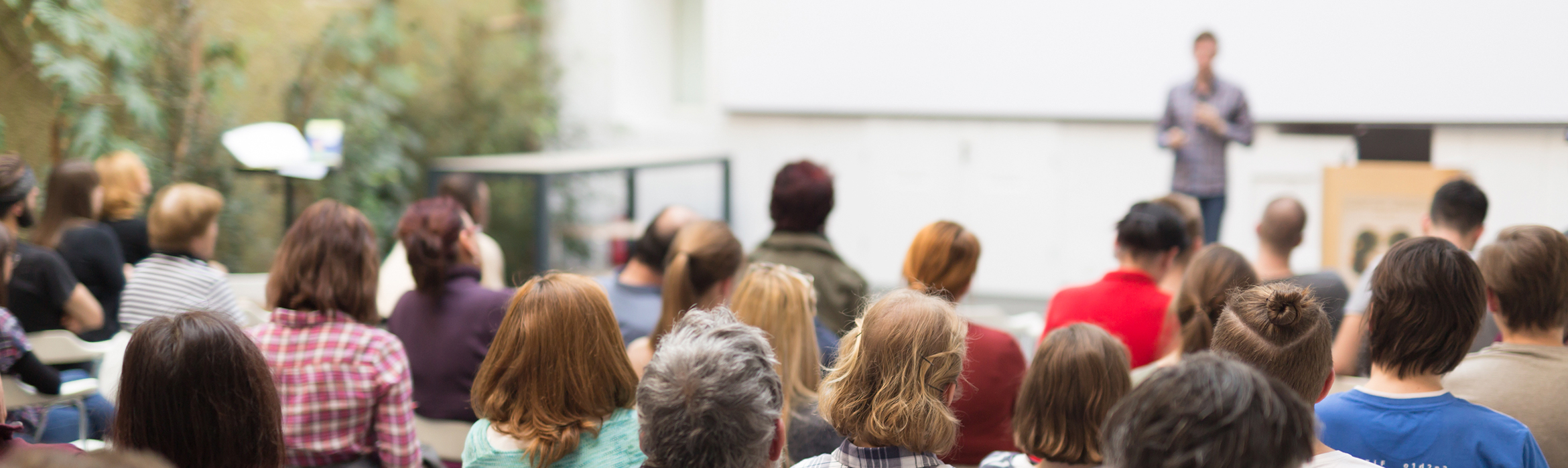 Una conferencia es impartida al aire libre, el público lo componen personas de diferentes edades