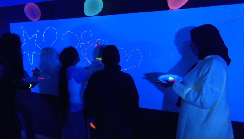 imagen de estudiantes desarrollando una actividad con luz negra alumnos realizando una actividad de luz negra