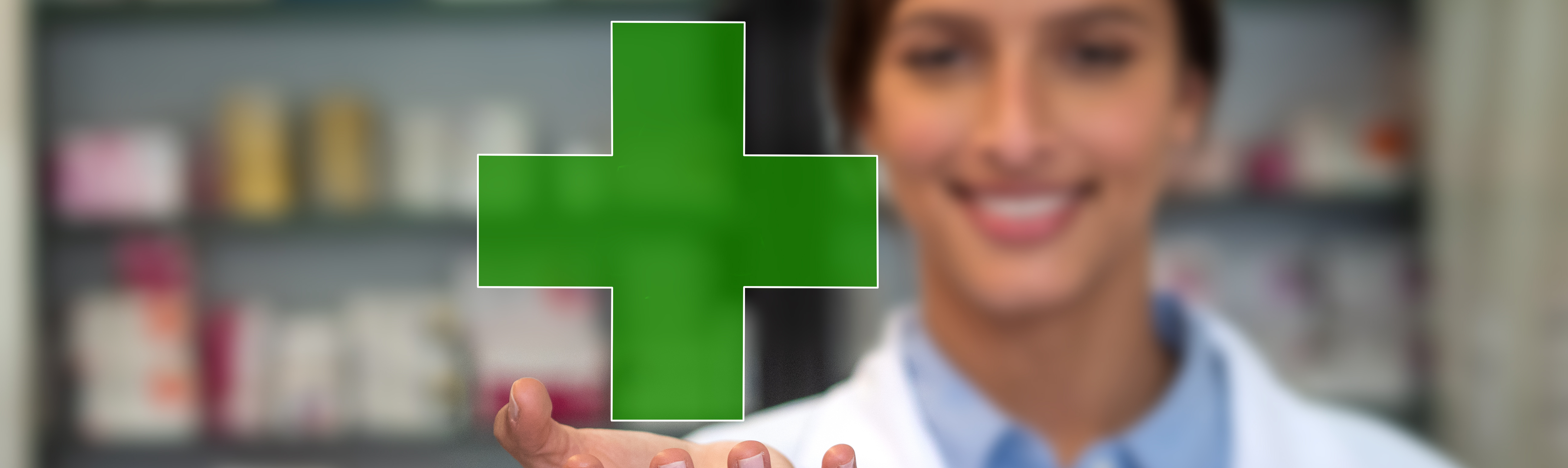 Farmacéutica sonriendo en el interior de una farmacia y mostrando una cruz verde en sus manos