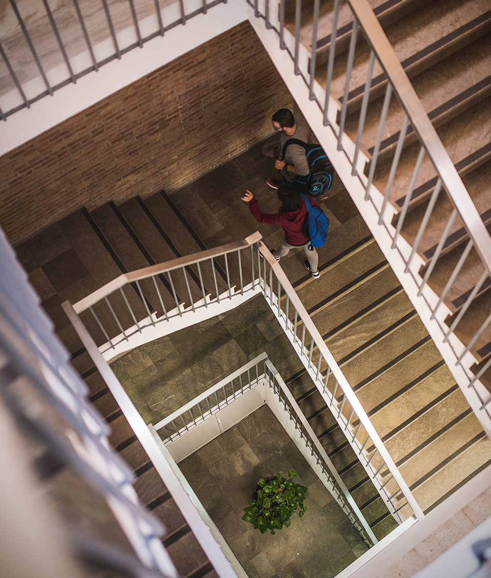 Dos estudiantes subiendo unas de las escaleras de la Escuela Técnica Superior de Ingeniería de Caminos, Canales y Puertos
