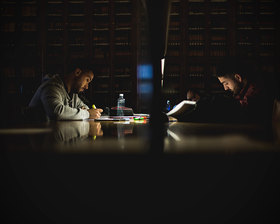 Estudiantes en las mesas de estudio de la biblioteca del Hospital Real leyendo sus apuntes