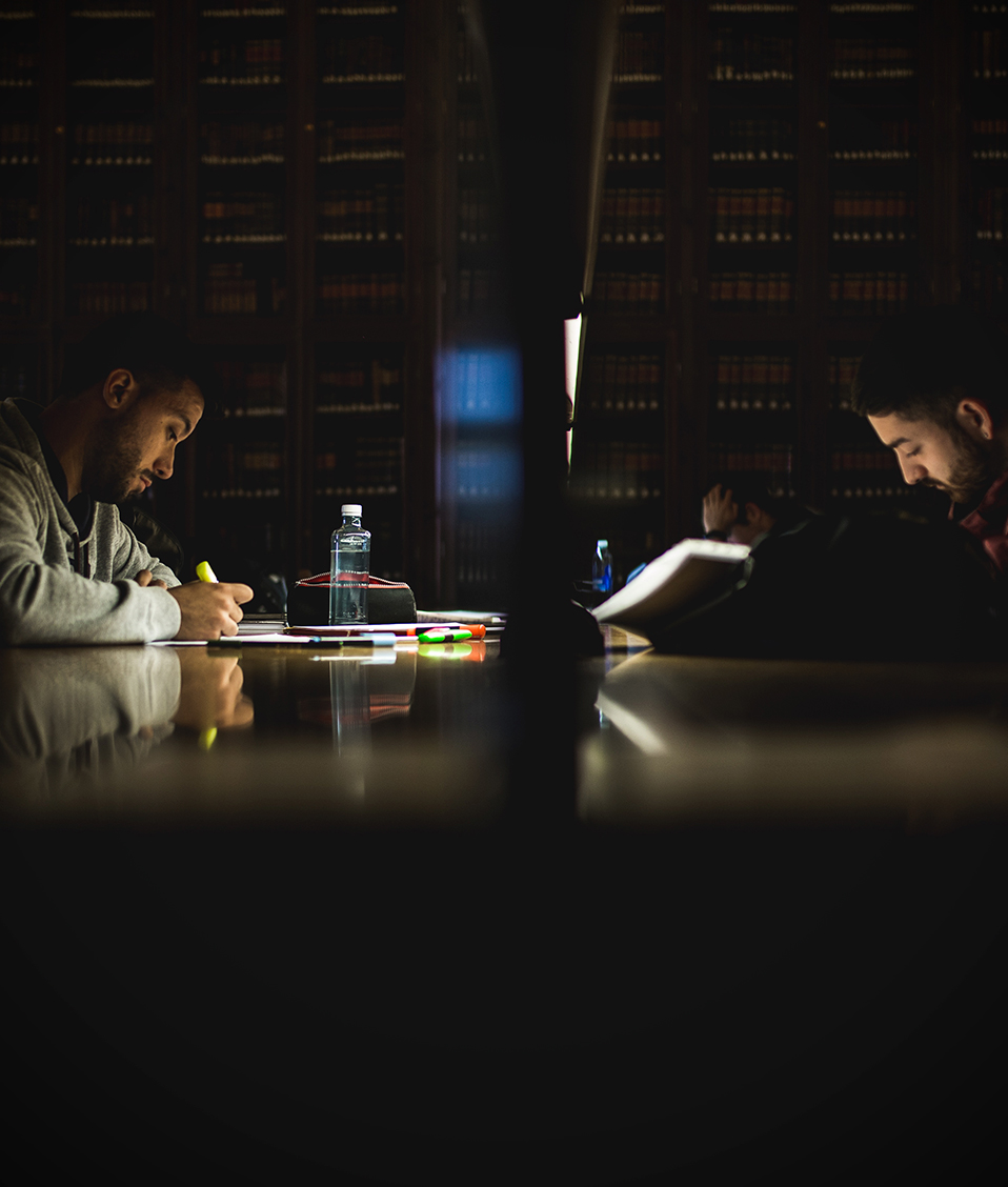 Estudiantes en las mesas de estudio de la biblioteca del Hospital Real leyendo sus apuntes