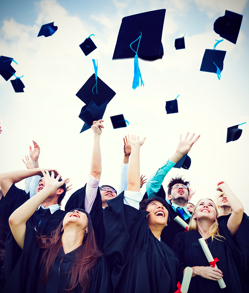 Estudiantes celebrando su graduación tirando hacia arriba sus birretes mientras sujetan su título en la mano