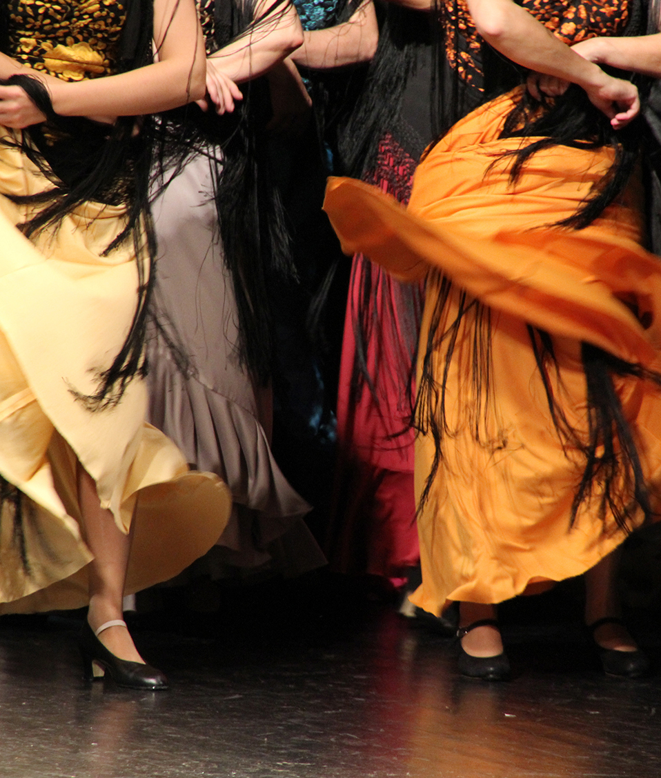 Varias personas bailando flamenco sobre un escenario con fondo negro