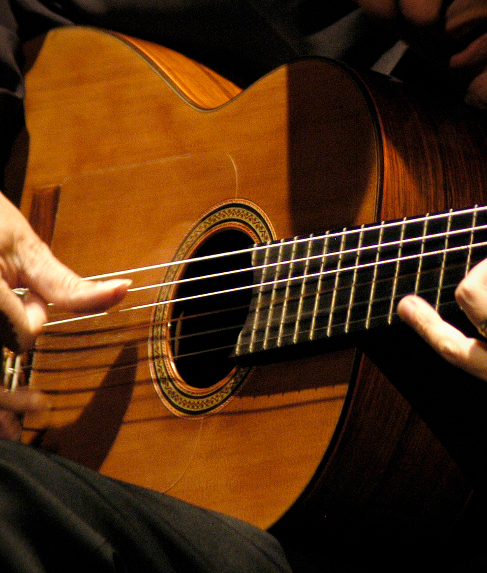 Persona tocando una guitarra flamenca con micrófono al lado
