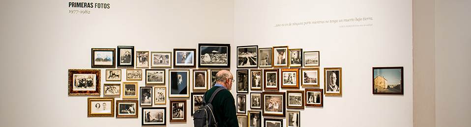 Hombre de lado observando fotografías en exposición en el Hospital Real