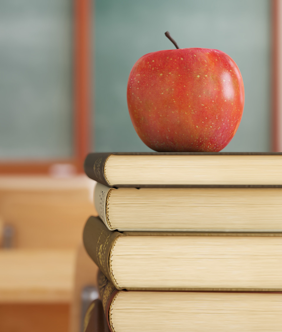 Manzana apoyada sobre varios libros en una aula vacía de escuela