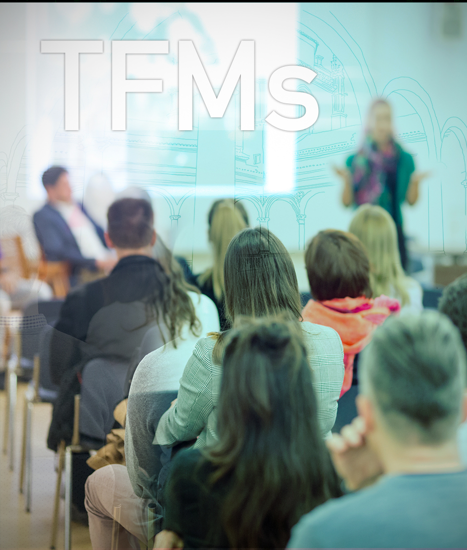 Las siglas TFMs que hacen referenci a Trabajos FIn de Master se muestra sobre la imagen de una conferencia
