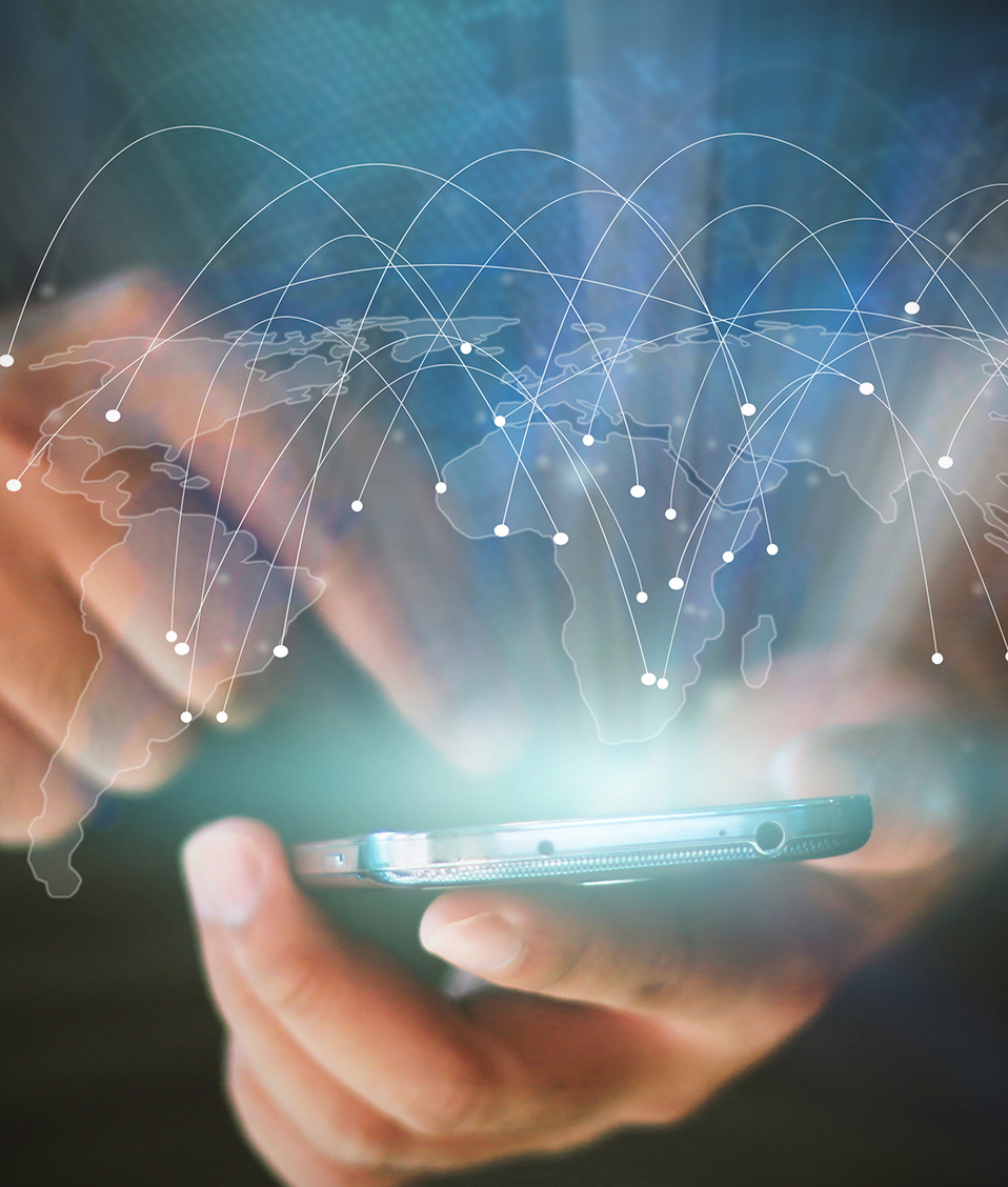 Las manos de una persona sujetan un smartphone. Del dispositivo surge un plano mundial en el que los paises aparecen interconectados gracias a la tecnología